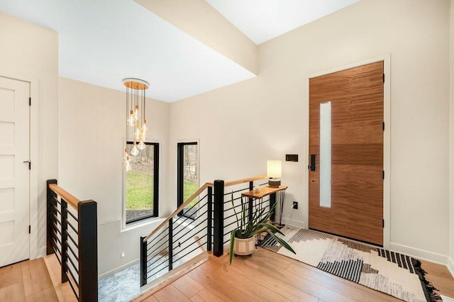 foyer entrance with baseboards, an inviting chandelier, and wood finished floors