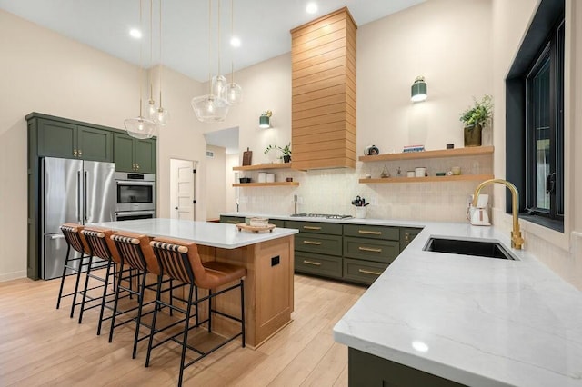 kitchen with green cabinets, a sink, open shelves, and stainless steel appliances