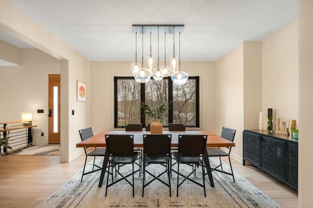 dining room featuring a chandelier, light wood-style floors, and baseboards