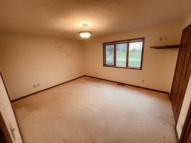 spare room with baseboards, visible vents, and light carpet