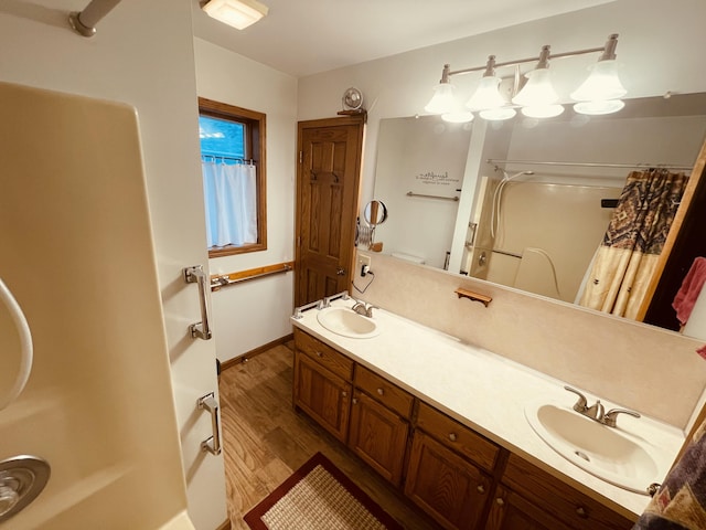 full bath featuring curtained shower, double vanity, wood finished floors, and a sink