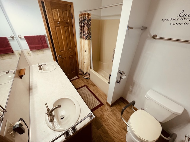 full bathroom with toilet, wood finished floors, double vanity, and a sink