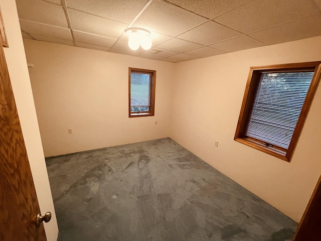 carpeted empty room featuring a drop ceiling