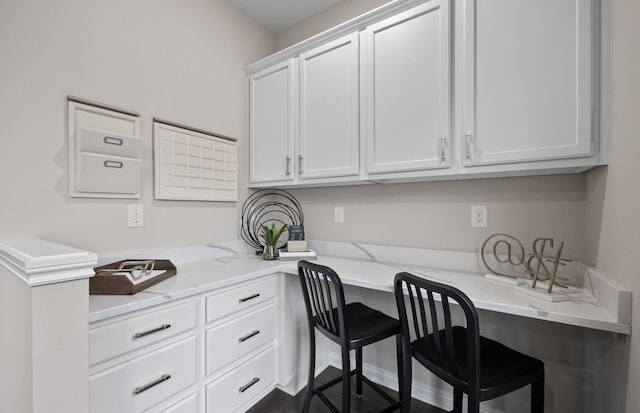 kitchen with white cabinets, built in study area, and light stone countertops
