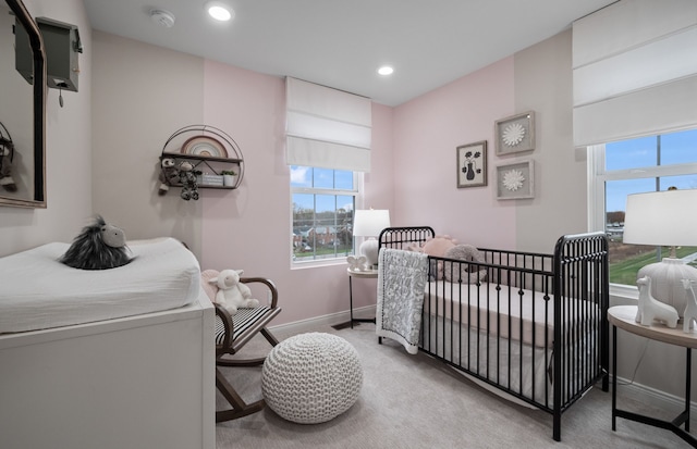 bedroom with baseboards, multiple windows, carpet, and a crib