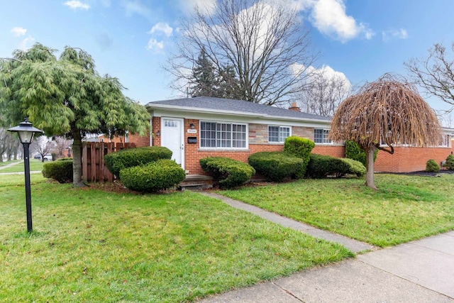 view of front of home featuring a chimney, fence, a front lawn, and brick siding