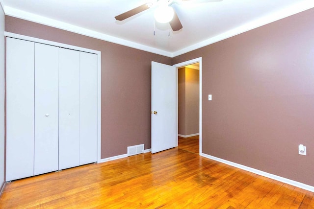 unfurnished bedroom featuring baseboards, a closet, a ceiling fan, visible vents, and light wood finished floors