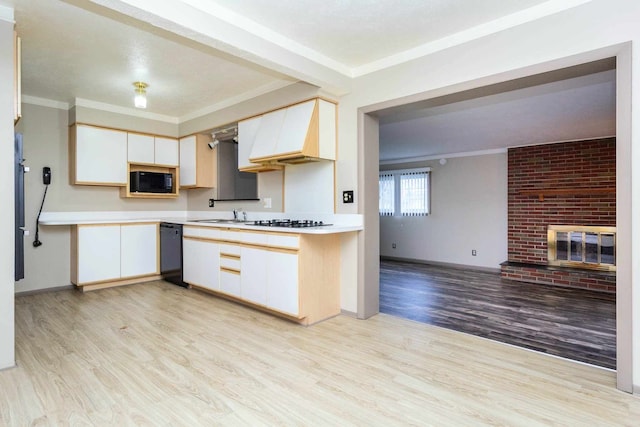 kitchen featuring light wood finished floors, light countertops, ornamental molding, and black appliances