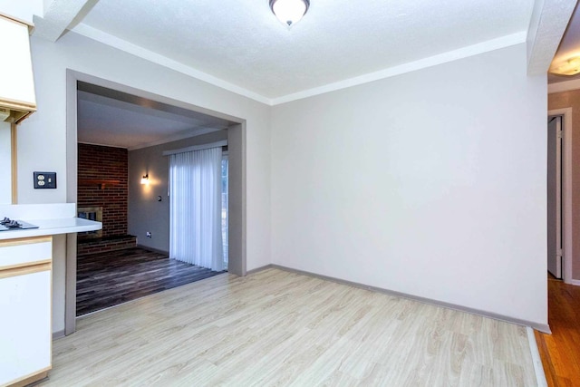 interior space with light wood-style flooring, ornamental molding, and a brick fireplace