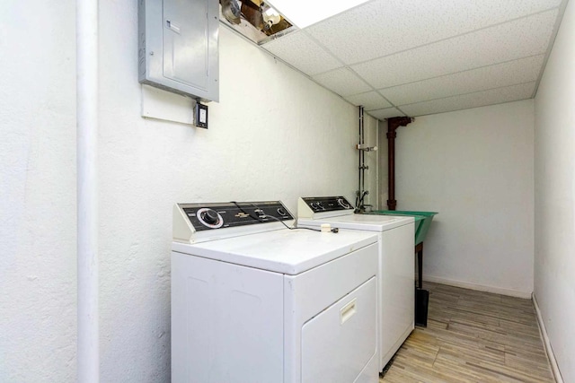 laundry room with laundry area, light wood-style flooring, electric panel, washer and dryer, and baseboards
