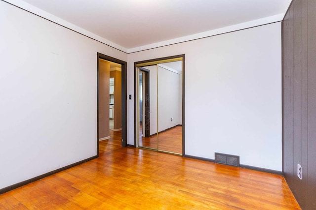 empty room featuring light wood-style floors, visible vents, and baseboards