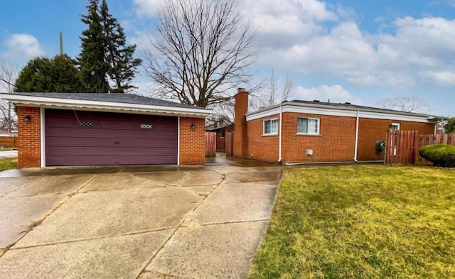 view of front of home with a front yard, brick siding, fence, and a detached garage
