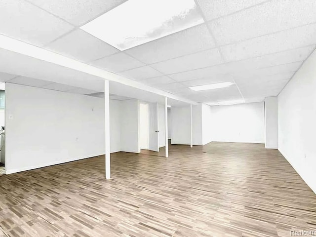 finished basement with a paneled ceiling and wood finished floors