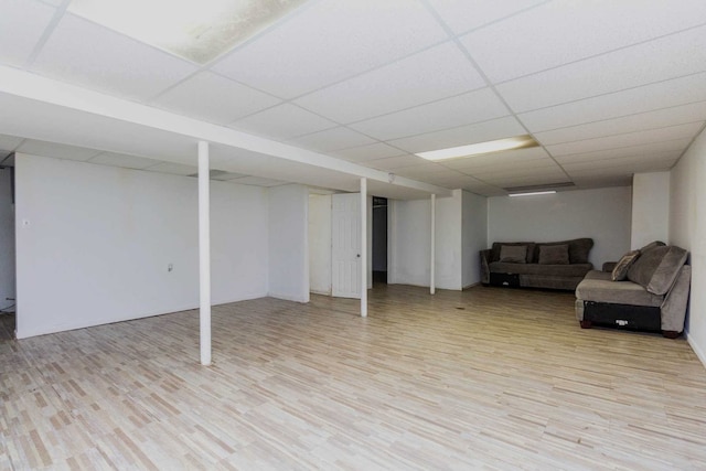 finished below grade area featuring light wood-style floors and a paneled ceiling