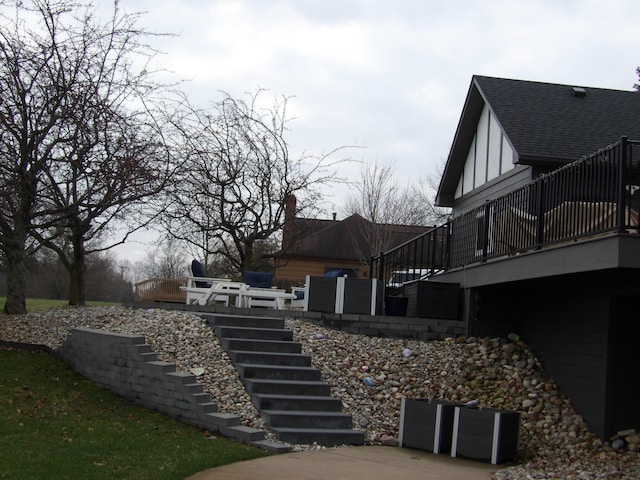 view of side of property with a chimney, a deck, and stairs