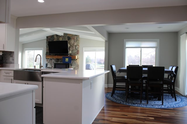 kitchen featuring lofted ceiling with beams, dark wood finished floors, white cabinetry, light countertops, and a sink