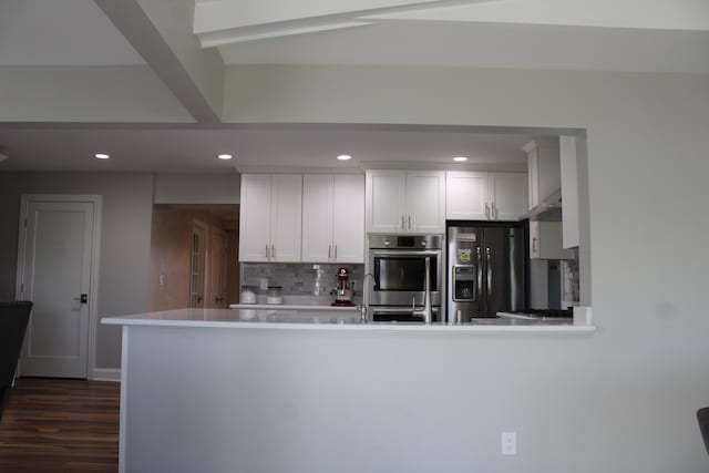 kitchen featuring light countertops, white cabinetry, black fridge, backsplash, and stainless steel double oven