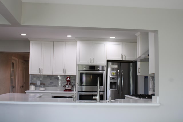 kitchen featuring fridge with ice dispenser, light countertops, under cabinet range hood, backsplash, and stainless steel double oven