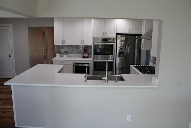 kitchen with tasteful backsplash, light countertops, black fridge with ice dispenser, stainless steel double oven, and a sink