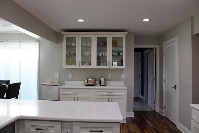 kitchen with baseboards, glass insert cabinets, light countertops, white cabinets, and dark wood finished floors