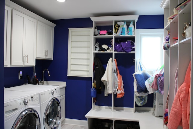 washroom with cabinet space, washing machine and clothes dryer, and a sink