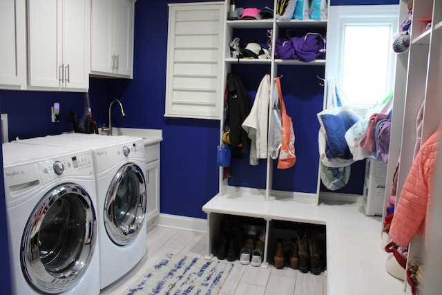 clothes washing area with washer and dryer, baseboards, a sink, and cabinet space