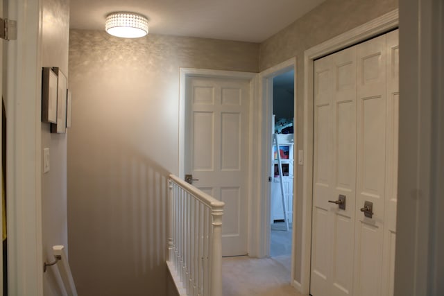hall featuring light carpet and an upstairs landing