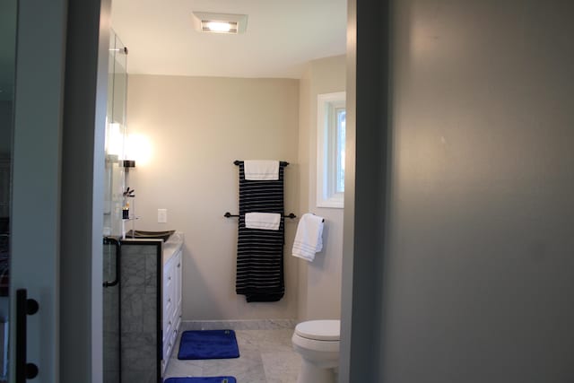 full bath featuring marble finish floor, vanity, baseboards, and toilet