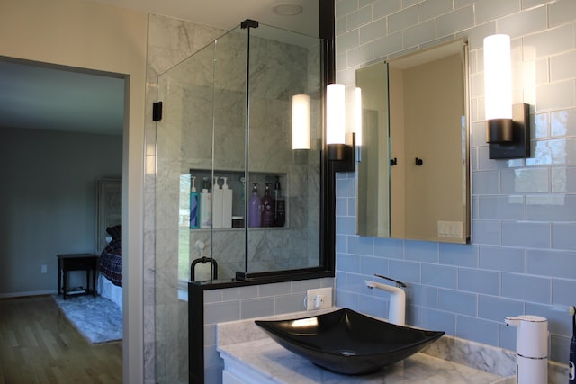bathroom with a sink, tasteful backsplash, a stall shower, and wood finished floors
