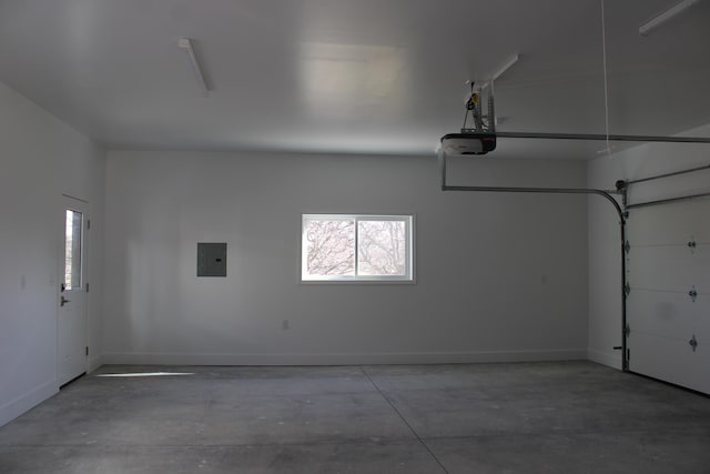 garage featuring a garage door opener, baseboards, and electric panel