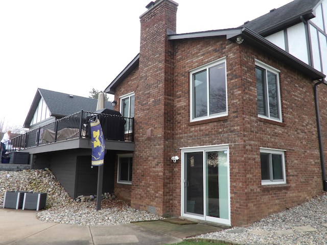 rear view of property featuring a chimney, a deck, and brick siding