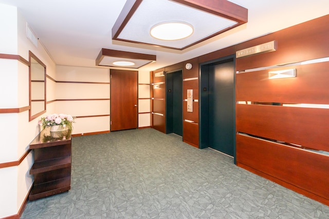 1050 Wall St Unit 3C, Ann Arbor, MI 48105 - hallway with elevator, tile patterned floors, a tray ceiling, and baseboards
