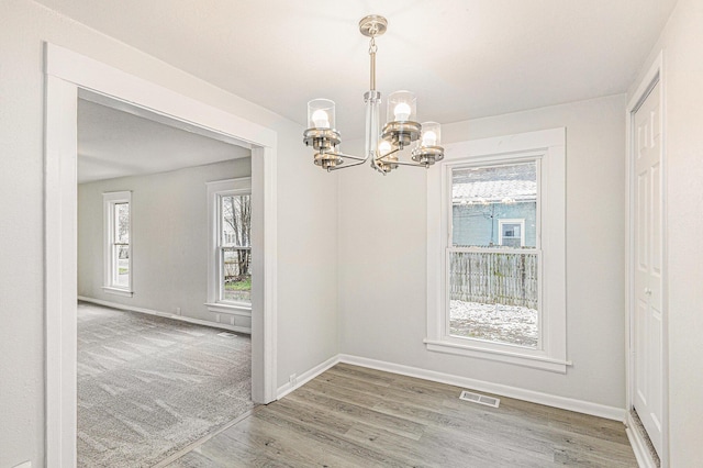 804 Lincoln St, Jackson, MI 49202 - unfurnished dining area featuring a chandelier, wood finished floors, baseboards, and visible vents