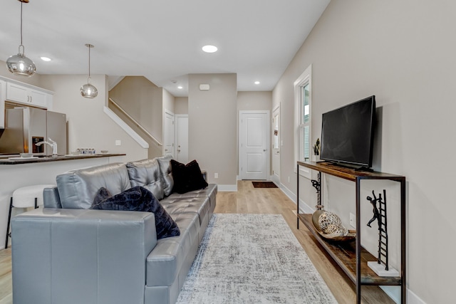living room featuring light wood-style flooring, baseboards, stairway, and recessed lighting