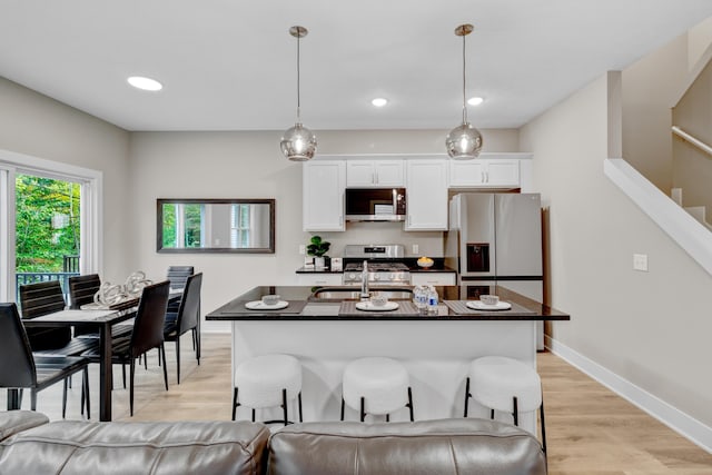 kitchen featuring dark countertops, white cabinets, appliances with stainless steel finishes, and a sink