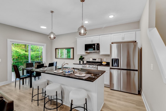 kitchen with dark countertops, a sink, white cabinetry, and stainless steel appliances