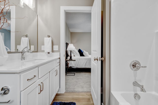 ensuite bathroom featuring shower / bath combination, ensuite bath, vanity, and wood finished floors