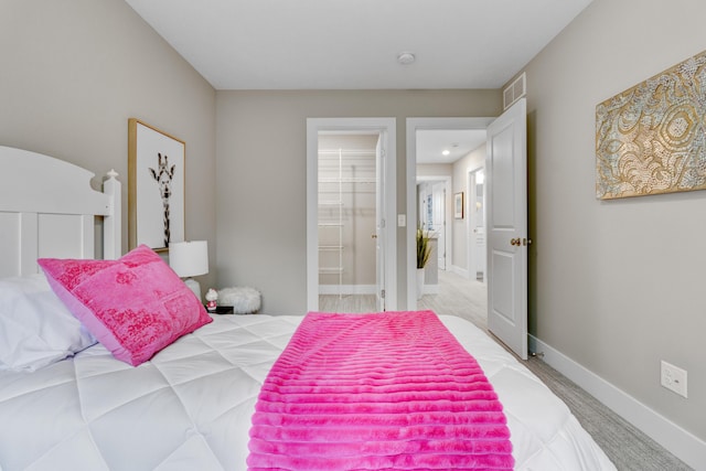 bedroom featuring visible vents, baseboards, ensuite bathroom, and light colored carpet
