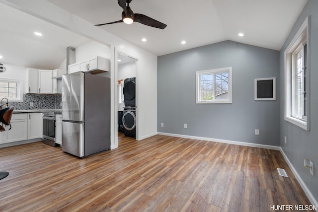 175 Cora Ave, Muskegon, MI 49445 - kitchen with stacked washer and dryer, visible vents, vaulted ceiling, and stainless steel appliances