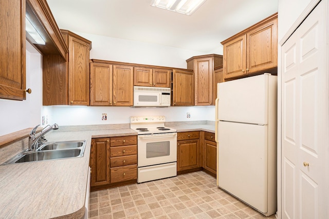 kitchen featuring light countertops, brown cabinetry, a sink, and white appliances