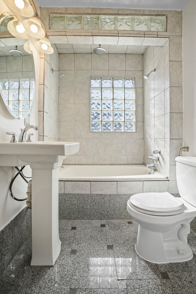 full bath with toilet, granite finish floor, and tiled shower / bath