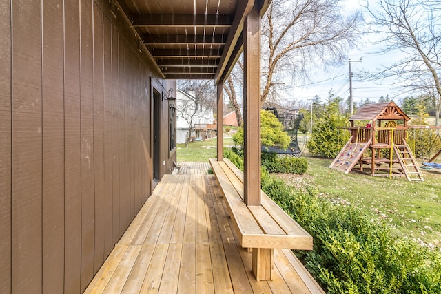 wooden deck featuring a lawn, a trampoline, and a playground