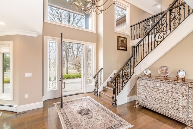 foyer with dark wood-type flooring, a towering ceiling, visible vents, and a healthy amount of sunlight