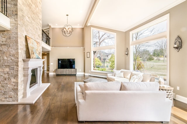 living room featuring a glass covered fireplace, wood finished floors, crown molding, and a high ceiling