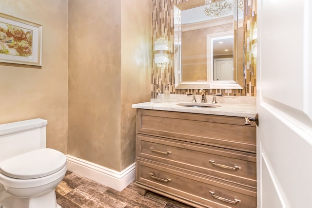 bathroom with wood finished floors, vanity, toilet, and baseboards