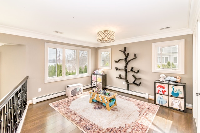 recreation room with ornamental molding, baseboard heating, and wood finished floors