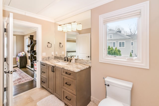 bathroom with crown molding, toilet, vanity, and a healthy amount of sunlight