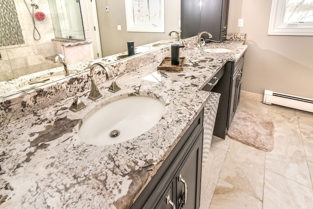 bathroom featuring double vanity, a walk in shower, a baseboard heating unit, and a sink