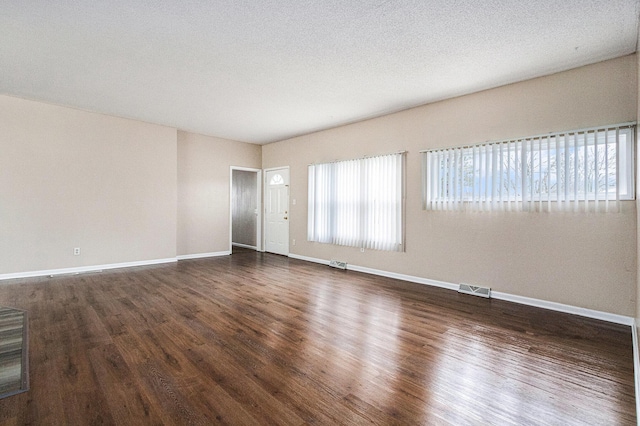 unfurnished room with dark wood-type flooring, baseboards, and visible vents