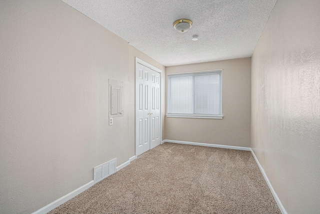 spare room featuring visible vents, baseboards, carpet floors, and a textured ceiling